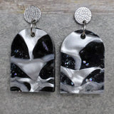 A pair of one of a kind arch shaped recycled acrylic earrings with black and white design titled 'Lunar Edge' and stainless steel toppers. Pair 104-02