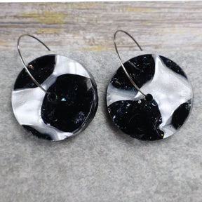 A pair of one of a kind recycled acrylic disc shaped earrings on stainless steel hoops with multicolored design titled 'Lunar Edge'. Pair 104-07