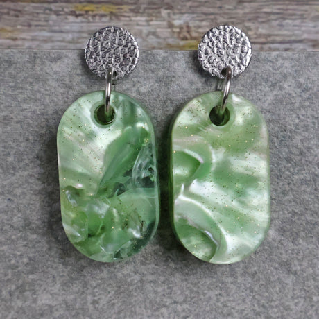 Pair of one of a kind small oval shaped recycled acrylic earrings featuring green acrylics and stainless steel toppers. Pair 105-01