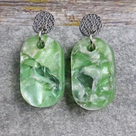 Pair of one of a kind small oval shaped recycled acrylic earrings featuring green acrylics and stainless steel toppers. Pair 105-02