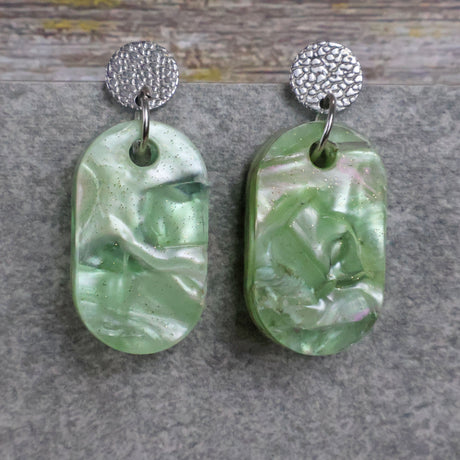 Pair of one of a kind small oval shaped recycled acrylic earrings featuring green acrylics and stainless steel toppers. Pair 105-03