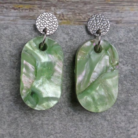 Pair of one of a kind small oval shaped recycled acrylic earrings featuring green acrylics and stainless steel toppers. Pair 105-04