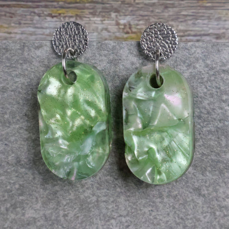 Pair of one of a kind small oval shaped recycled acrylic earrings featuring green acrylics and stainless steel toppers. Pair 105-08