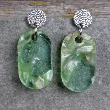 Pair of one of a kind small oval shaped recycled acrylic earrings featuring green acrylics and stainless steel toppers. Pair 105-09