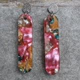 Pair of one of a kind long bar shaped acrylic earrings with multicolored  design titled 'Sunset Reef' and stainless steel toppers on a gray background. Pair 106-06