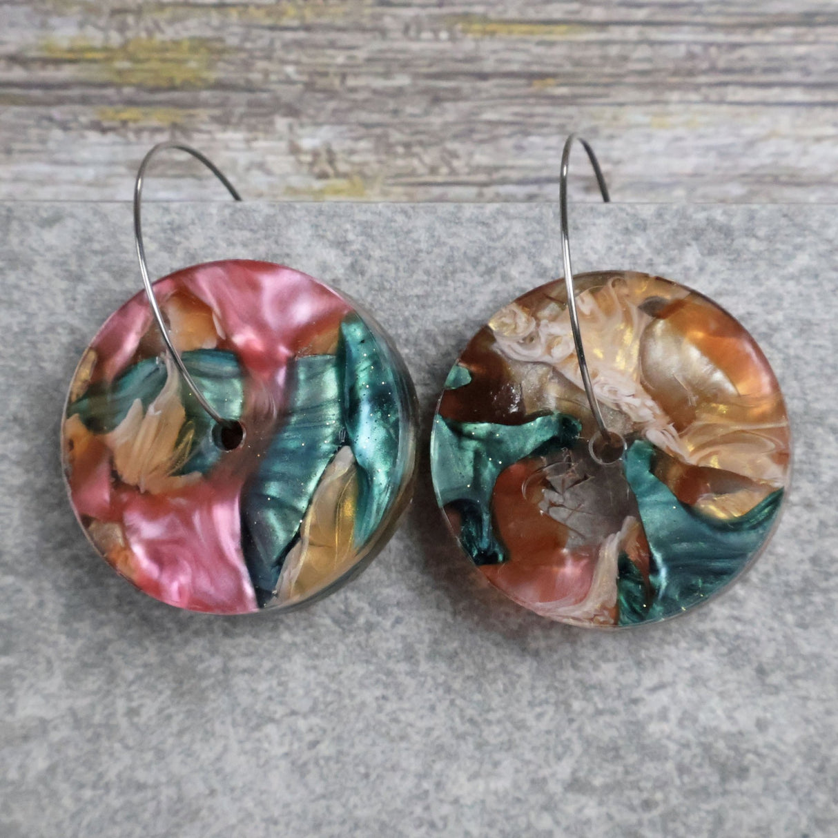 Pair of one of a kind disc acrylic earrings on stainless steel hoops with multicolored design titled 'Sunset Reef'. Pair 106-012