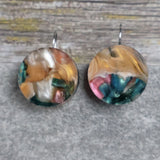 
A pair of one of a kind round recycled acrylic earrings with stainless steel french hooks and multicolored design titled 'Sunset Reef'. Pair 106-17