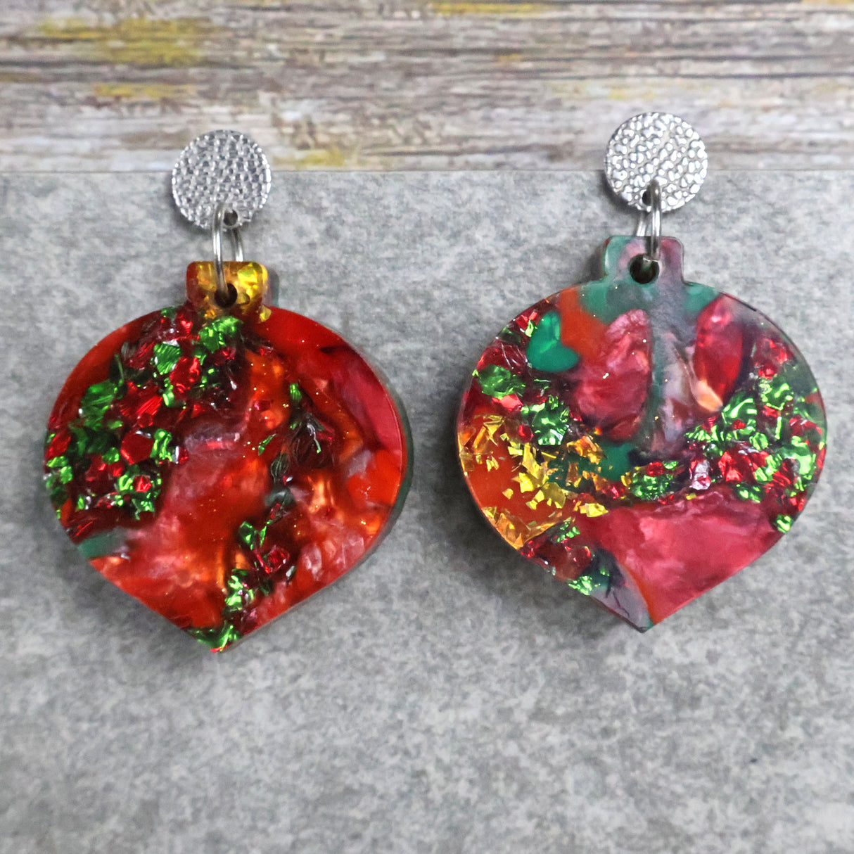 A pair of one of a kind recycled acrylic Christmas bauble earrings with stainless steel toppers, featuring a red, green and gold acrylic design. Pair 107-05