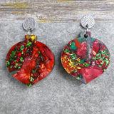 A pair of one of a kind recycled acrylic Christmas bauble earrings with stainless steel toppers, featuring a red, green and gold acrylic design. Pair 107-05