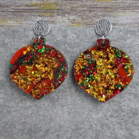 A pair of one of a kind recycled acrylic Christmas bauble earrings with stainless steel toppers, featuring a red, green and gold acrylic design. Pair 107-07