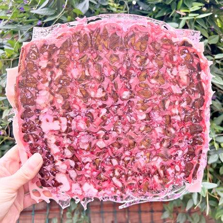 A melt pressed recycled acrylic sheet showing a randomised assortment of pink coloured acrylic scraps pressed within. Sheet titled 'Dusky Petals'.