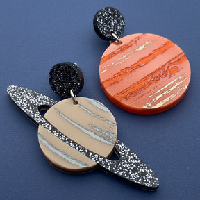 A pair of asymmetrical earrings, of Jupiter and Saturn. Laser cut from acrylic with handpainted details. 
