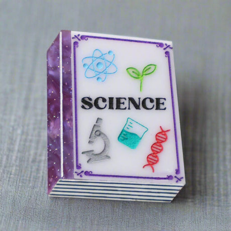 Small purple toned book brooch with 'SCIENCE' and related icons 