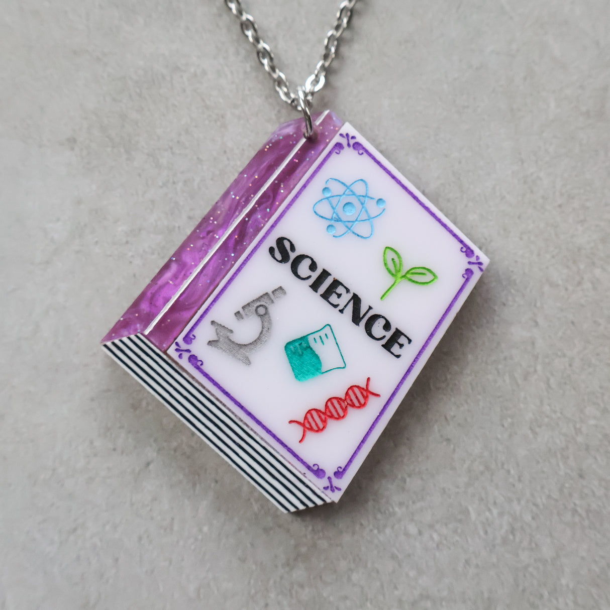 Closeup of a necklace with a science-themed textbook pendant 