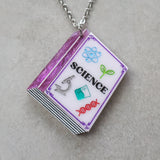 Closeup of a necklace with a science-themed textbook pendant 