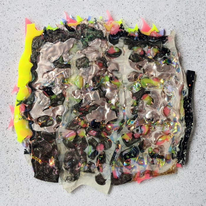 A square shaped sheet of acrylic that has been formed by melt pressing together various scraps. The sheet has a wide range of coloured and textured acrylics within.