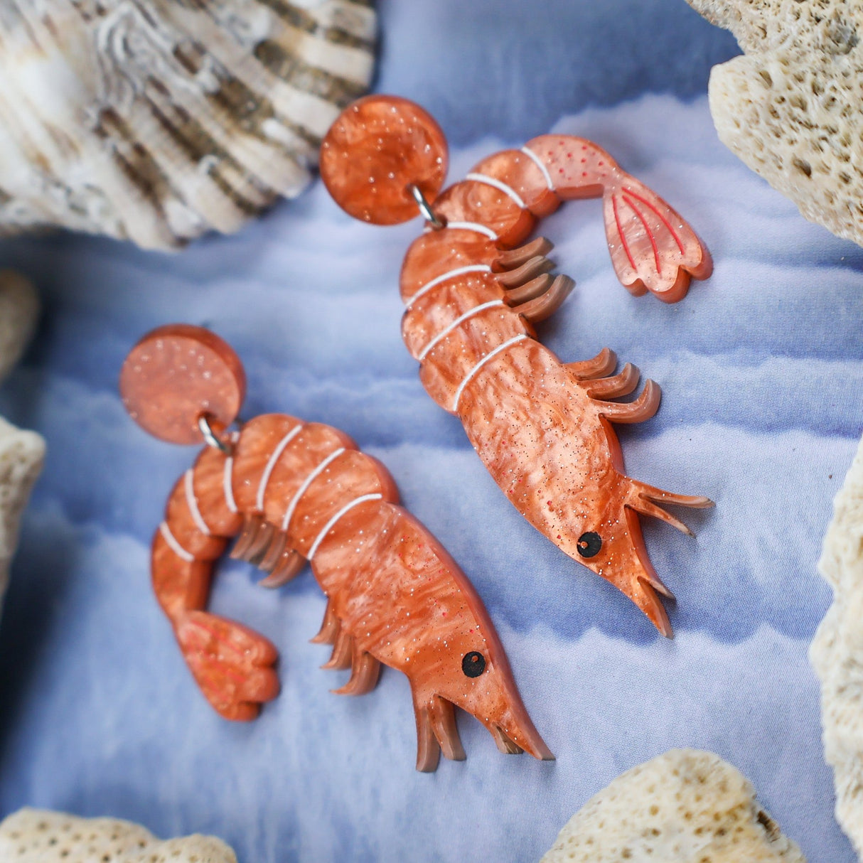Laser cut acrylic orange shrimp earrings, closeup.