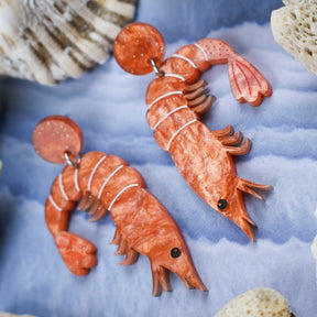 Laser cut acrylic orange shrimp earrings, closeup.