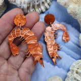 Laser cut acrylic orange shrimp earrings.