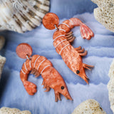 Laser cut acrylic orange shrimp earrings, closeup.