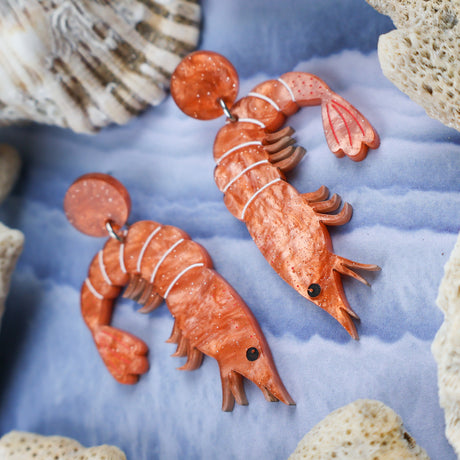 Laser cut acrylic orange shrimp earrings, closeup.