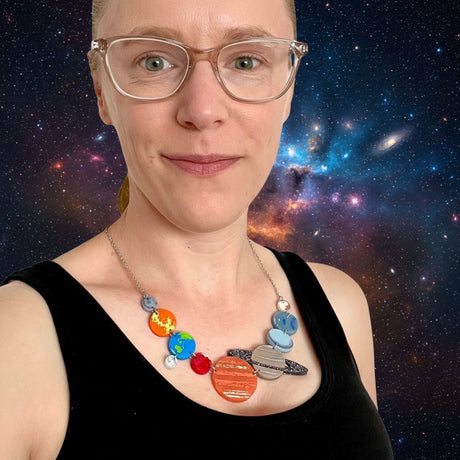 A person wearing a colorful solar system necklace made from laser cut acrylic.