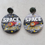 Earrings with 'Space Lover' design on a gray background with a meteor