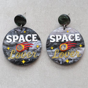 Earrings with 'Space Lover' design on a gray background with a meteor