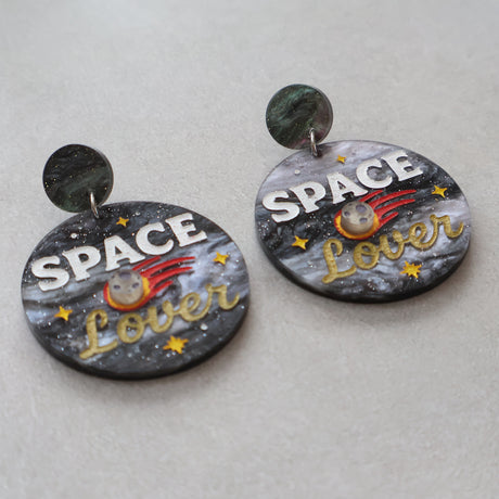 Earrings with 'Space Lover' design and a meteor on a light gray background