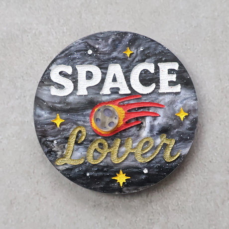 Circular acrylic brooch with 'Space Lover' text and space-themed design with a meteor