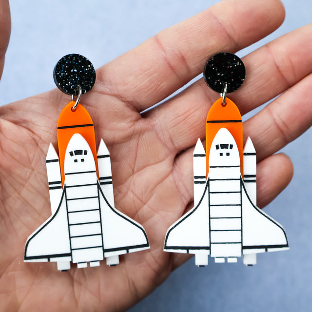 Laser cut acrylic space shuttle earrings in white, orange and black. 