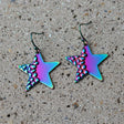 Star-shaped earrings with a metallic, iridescent finish on a gray background