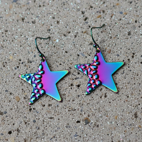 Star-shaped earrings with a metallic, iridescent finish on a gray background