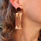 A closeup view of some brown toned stalactite and stalagmite dangle earrings being modelled. 