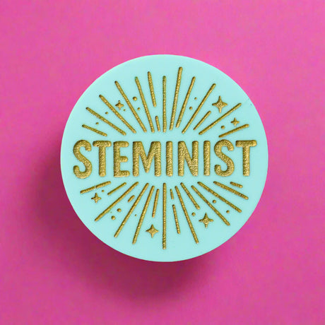 Round teal acrylic brooch with 'STEMINIST' in gold text