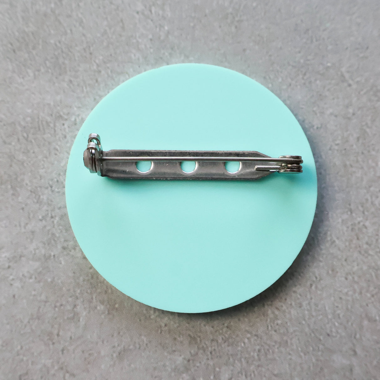 Teal brooch back showing stainless steel brooch pin and rolling clasp