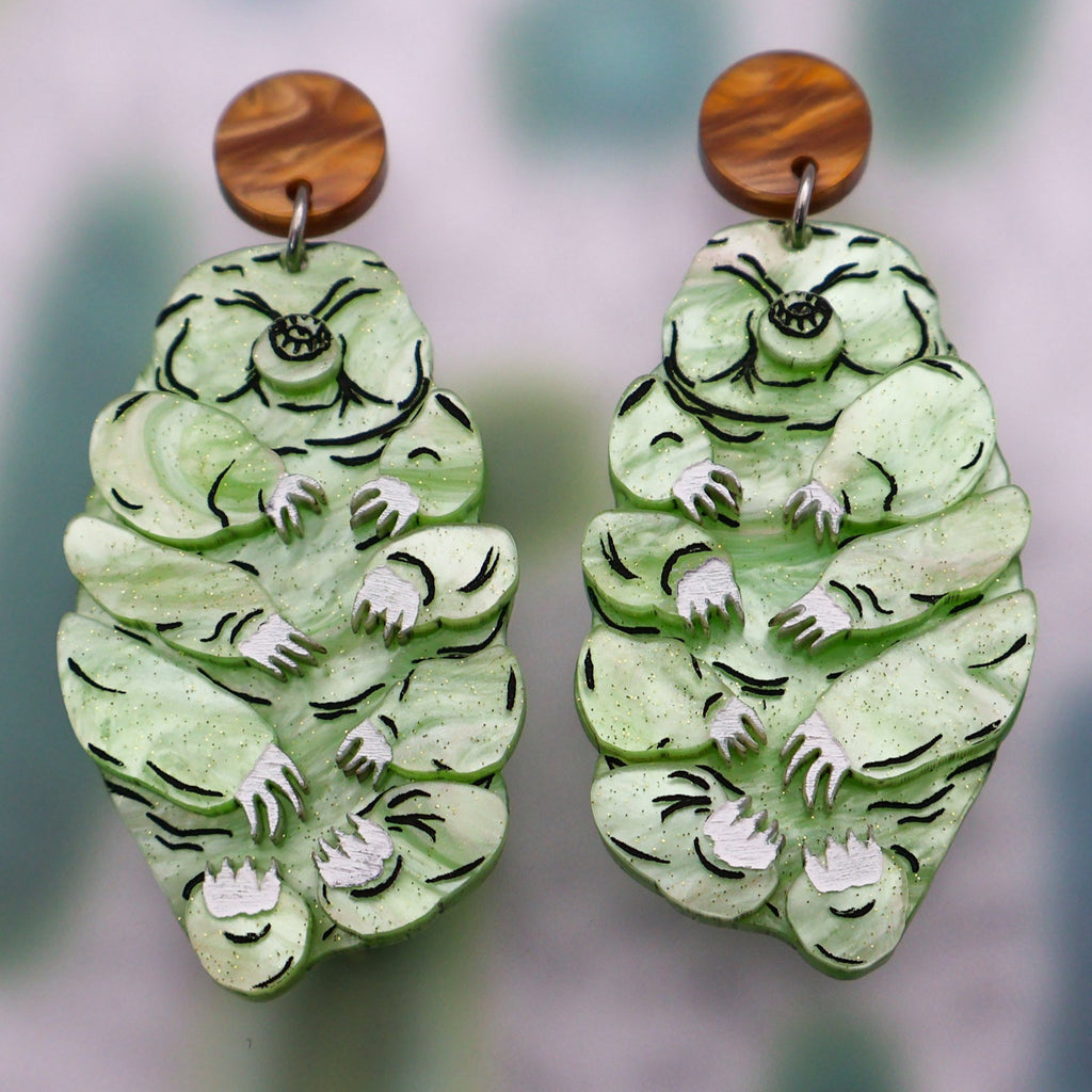 Tardigrade earrings made from swirly apple green acrylic, hanging from swirly brown round earring toppers. Handpainted details and multilayered design. 