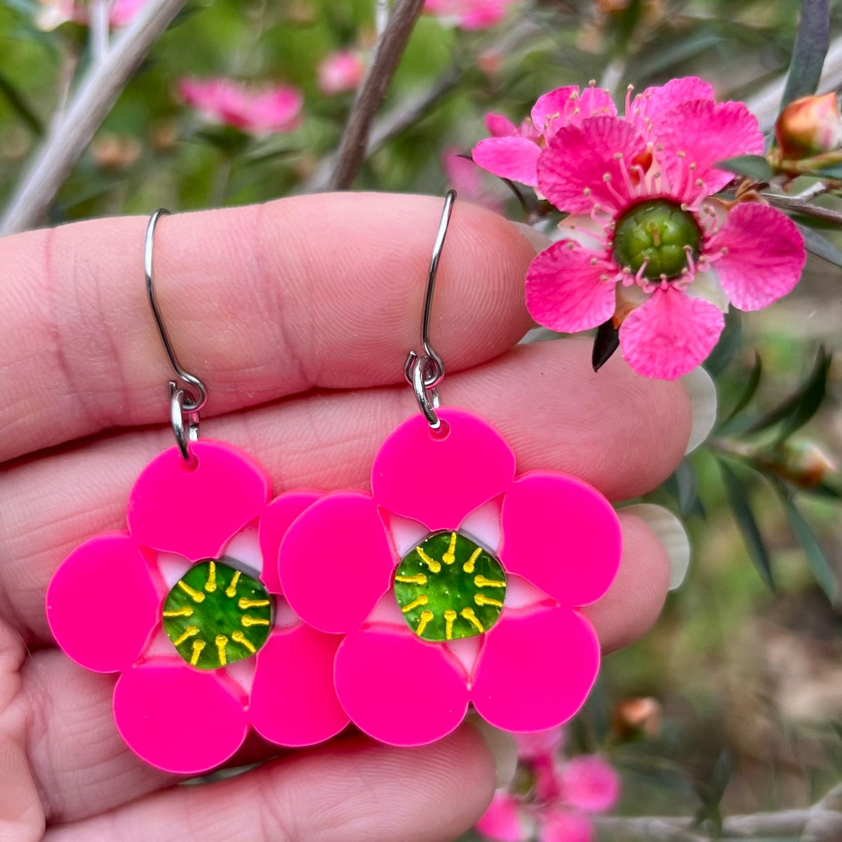 Tea tree Merinda flower earrings next to actual flowers of the same name.