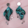 Pair of green marbled acrylic earrings with star charms and a wave shape, with silver mirror acrylic toppers. 