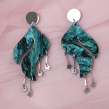 Pair of green marbled acrylic earrings with star charms and a wave shape, with silver mirror acrylic toppers. 