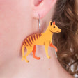 Acrylic thylacine earrings with stainless steel hoops worn on an ear