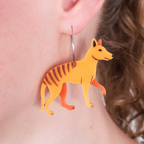 Acrylic thylacine earrings with stainless steel hoops worn on an ear