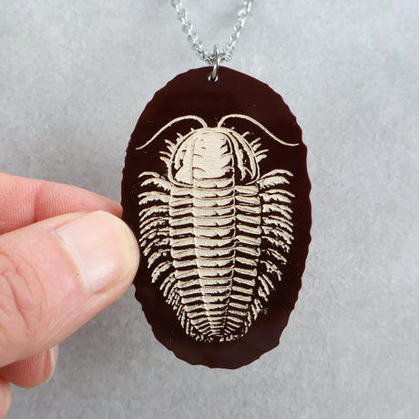 Faux fossilized acrylic trilobite pendant on a chain held by a hand
