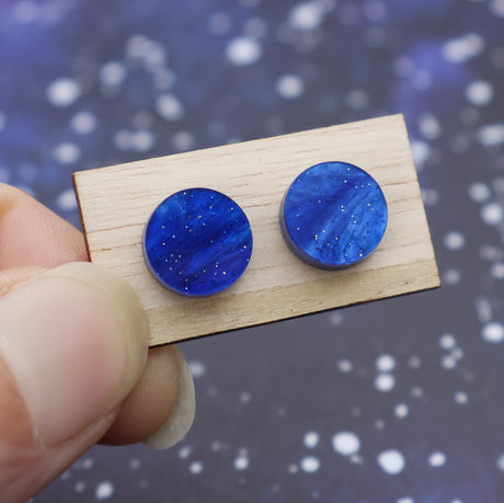 A pair of small blue acrylic 10mm diameter studs on a wooden backing card.
