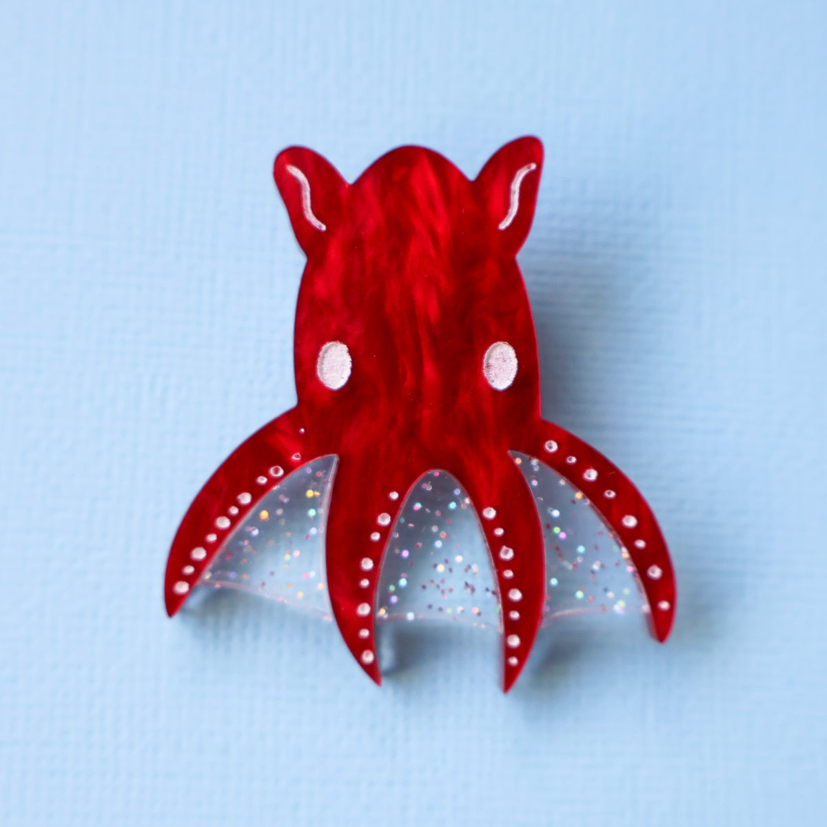 A red acrylic vampire squid against a blue backdrop