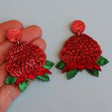 Acrylic waratah earrings being held in a hand