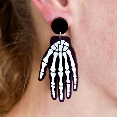 Skeletal hand-shaped earring worn on an ear
