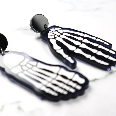 Skeletal hand and foot earrings on a white background