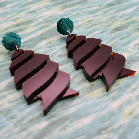 Angled view of brown cork-screw shark egg earrings with green acrylic toppers.
