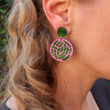 Close-up of a person wearing pink and green e.coli acrylic earrings. 